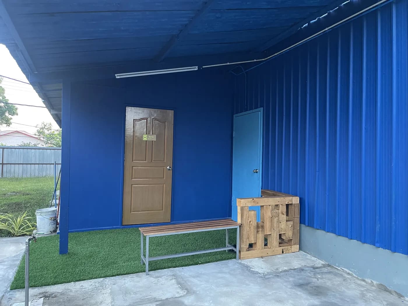 The entrance outside the hall, with a bench on the artificial grass