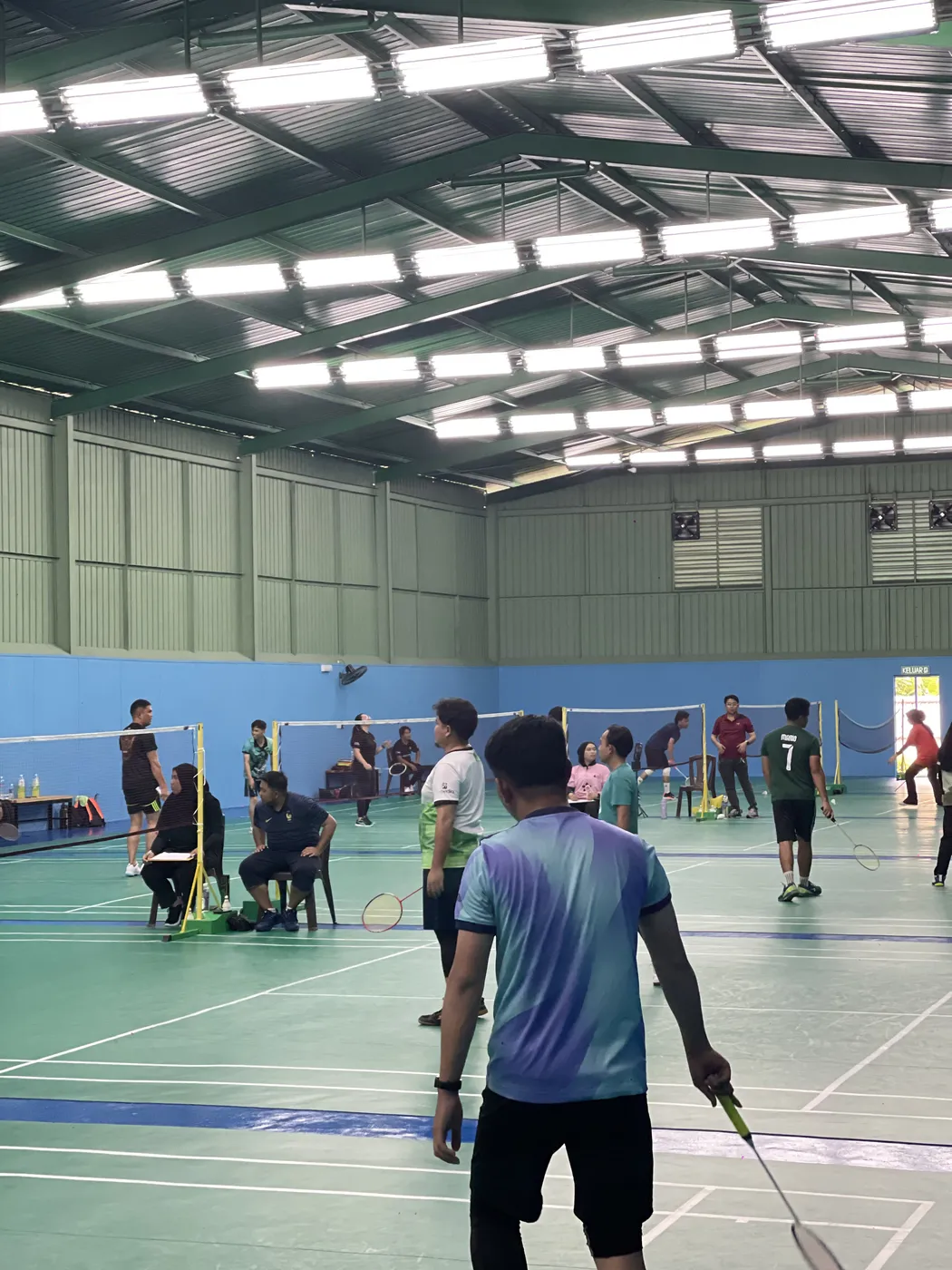 A player at the net, seen from the back of an adjacent court